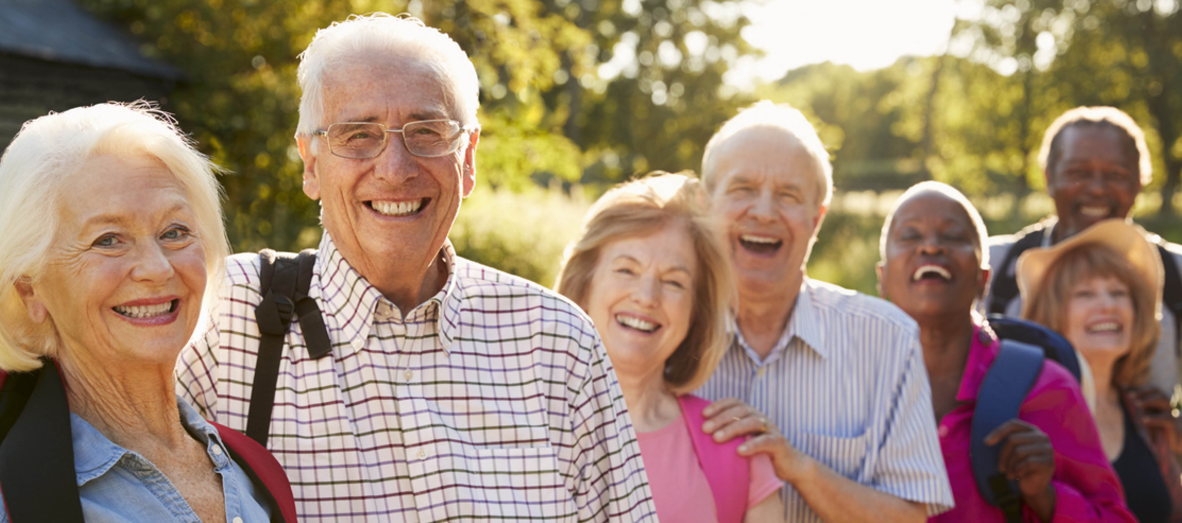 ältere Personen stehen hintereinander und lächeln in die Kamera