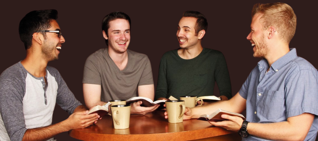 Vier Männer sitzten am Tisch und lachen, sprechen